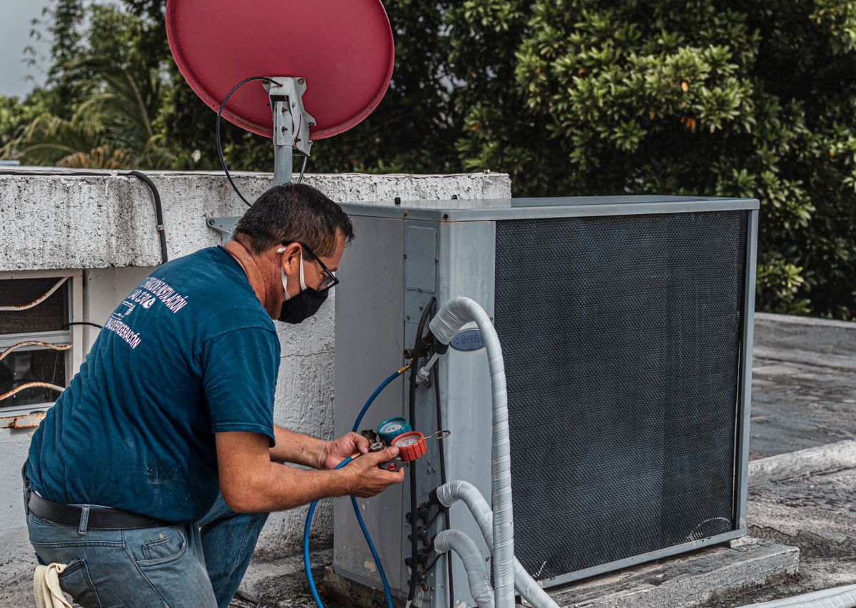 Technician repairing an air conditioner unit with a manifold gauge